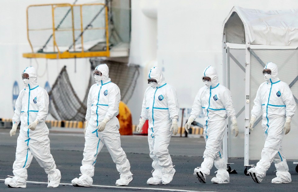  Workers wearing protective suits prepare to move infected passengers