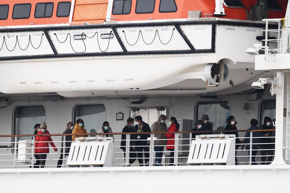  Passengers walk along the deck of the Diamond Princess cruise ship, with around 3,600 people quarantined on board