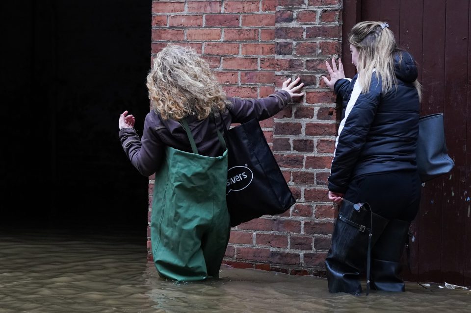  Two women wear waders to make their way into work as water levels in the River Ouse in York continue to rise