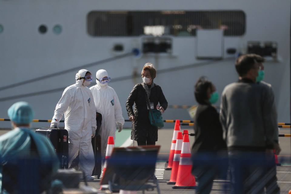  Workers wearing masks and protective suits are seen next to passengers wearing masks at Daikoku Pier Cruise Terminal, where cruise ship Diamond Princess is anchored