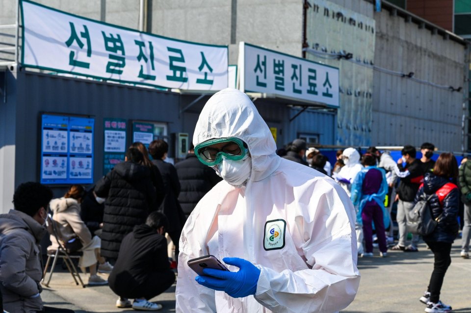  A hospital worker in a biohazard suit checks his phone at Daegu Medical Center Daegu, South Korea on Friday