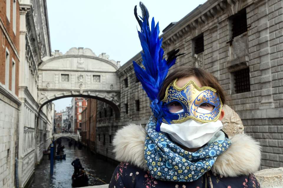  A young tourist wearing a protective face mask and a Carnival mask visits the streets of Venice