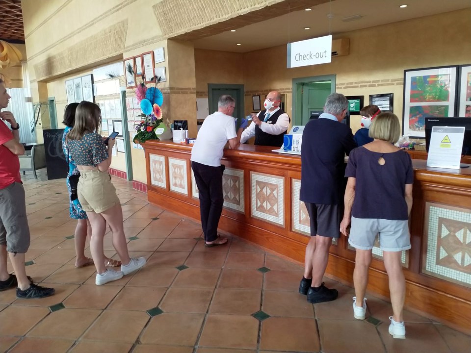 Members of staff are seen wearing face masks as they speak with guests inside the Adeje hotel