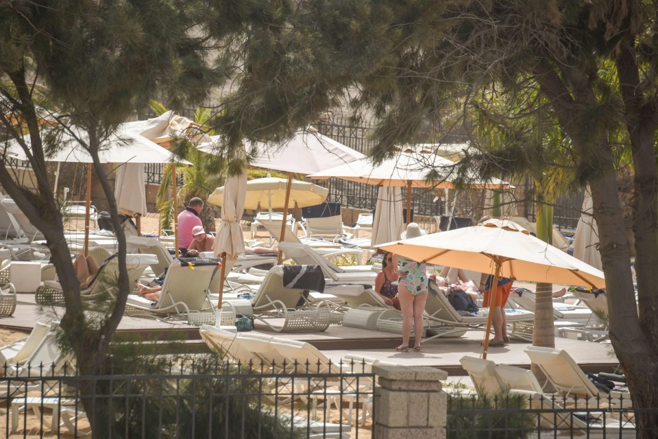 Tourists sunbath at the H10 Costa Adeje Palace Hotel while be held in quarantine