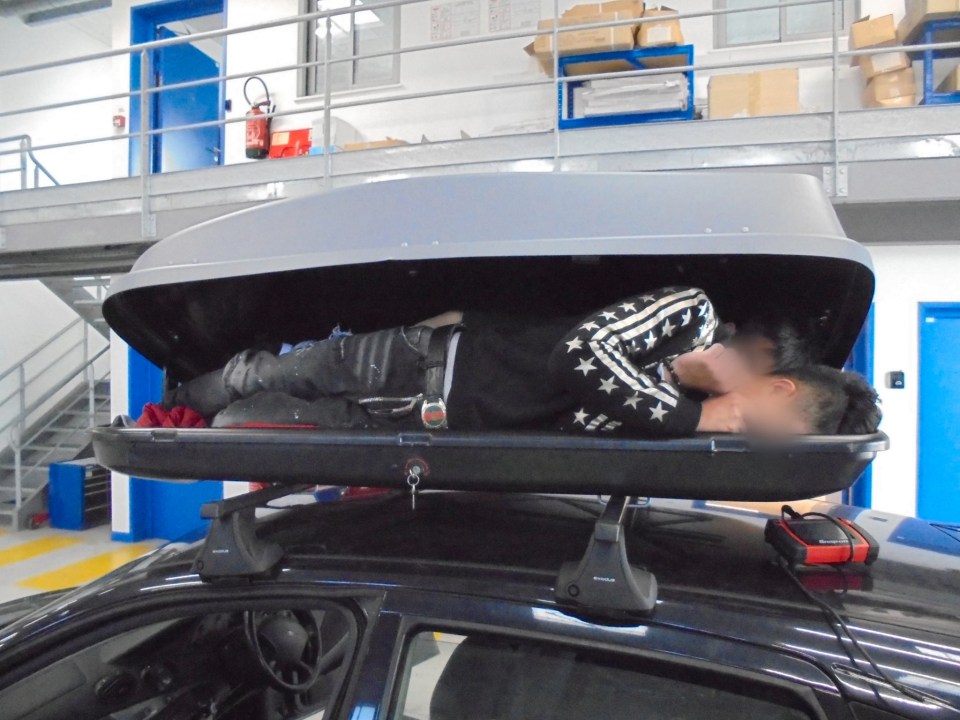  A Vietnamese national is seen crouched in a car roof box