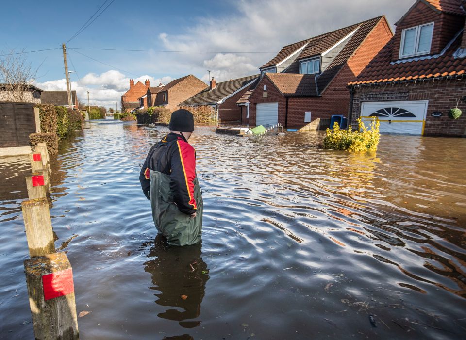  A man wades waist deep down a street in the village of East Cowick, Yorkshire