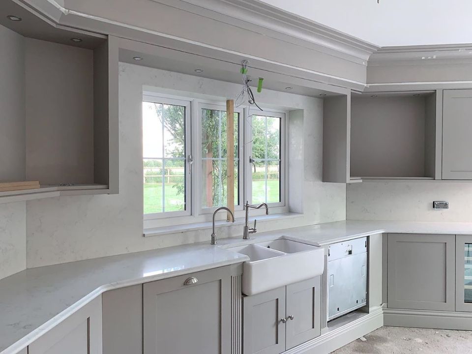  The kitchen boasts light grey cupboards and marble work tops