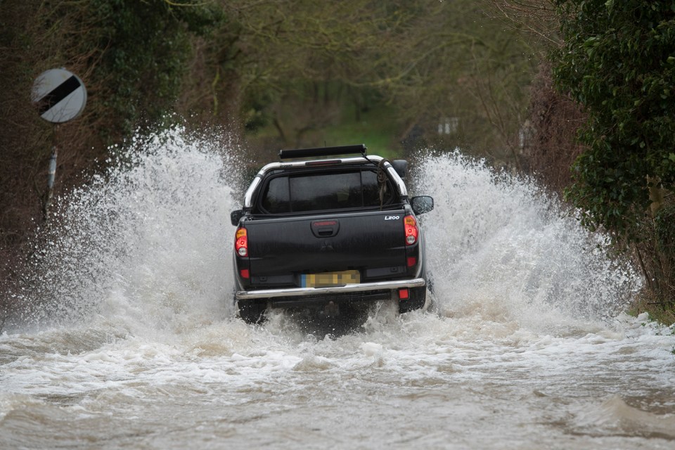  A motorist drives through a flooded road in Herts