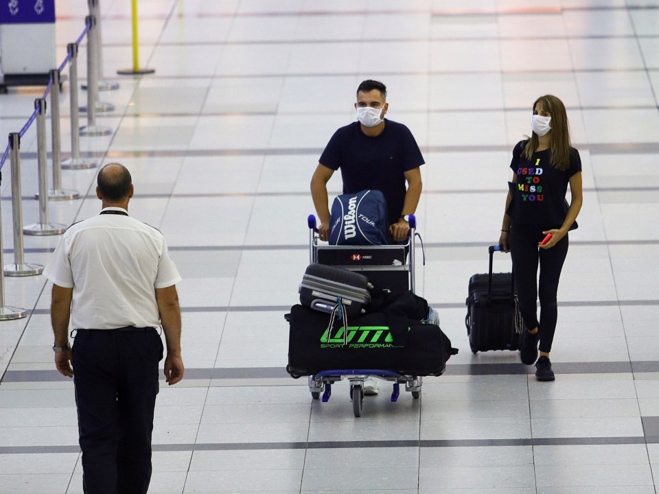  Travellers wear face masks as they get ready to check in for a flight