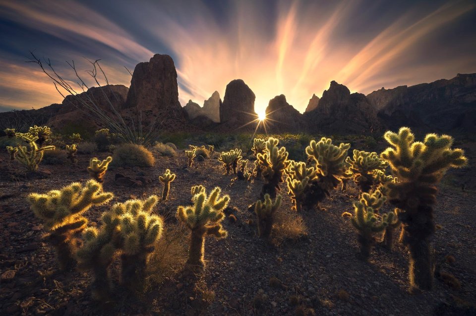 A low sun peeks between the peaks of the Kofa Mountains, Arizona