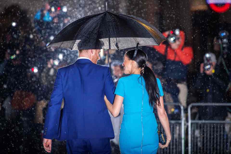 The couple cuddled up to shelter from the rain at Mansion House in London