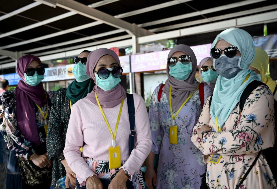  Women wear facemasks in Indonesia to control the spread of coronavirus as a British woman is confirmed dead