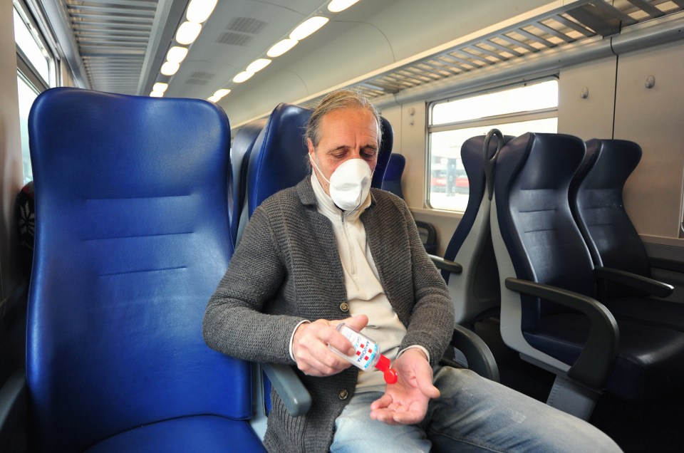  A man sitting in a train, wears mask and uses hand sanitiser gel as Italy battles a coronavirus outbreak