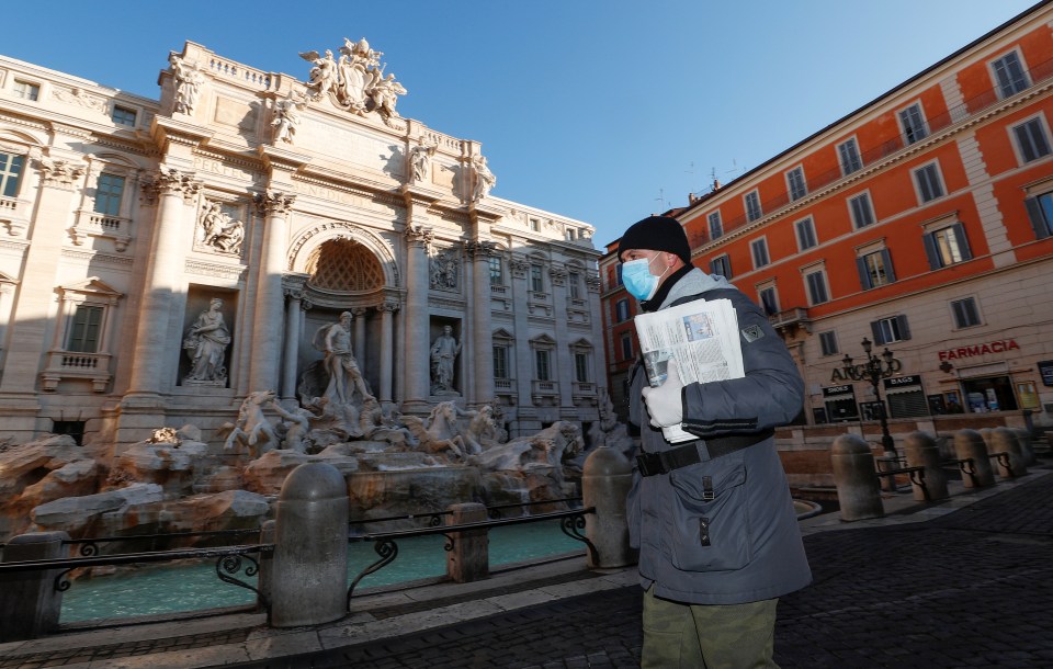  A man wearing a protective face mask walks next to the Trevi fountain in Rome on Tuesday