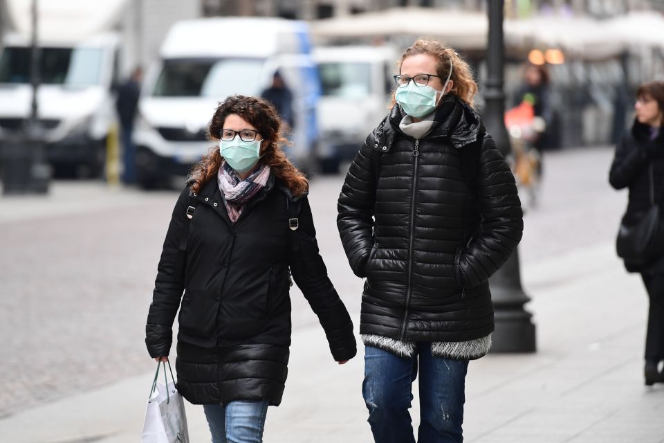  Pedestrians wearing a respiratory mask walk in downtown Milan on Tuesday morning