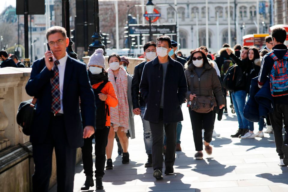  People wear protective face masks as they walk down Whitehall in London today as the coronavirus outbreak is declared a pandemic