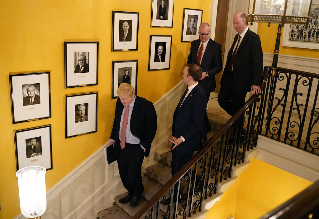 Boris Johnson, Matt Hancock and Chief Medical Officer Chris Whitty walk down the stairs together after press conference on the coronavirus on March 12