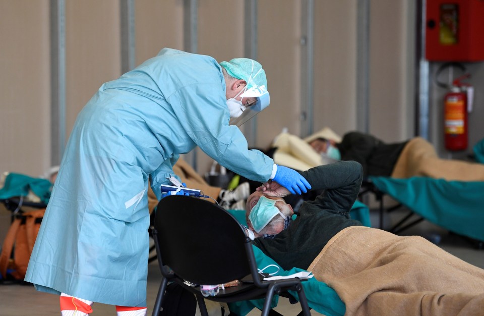  Medical staff wearing a protective face mask helps patients inside the Spedali Civili hospital in Brescia