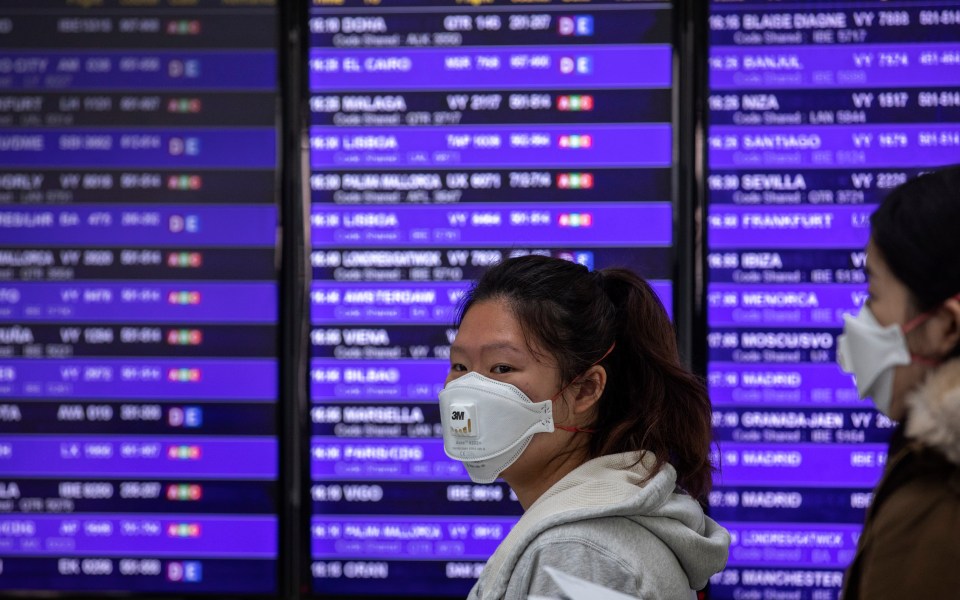  A woman walks in front of an arrival and departures board in Barcelona airport