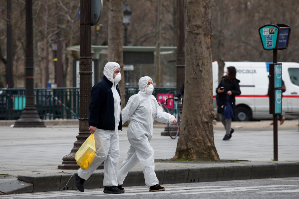  People wearing protective suits walk on the Champs Elysees Avenue in Paris this morning