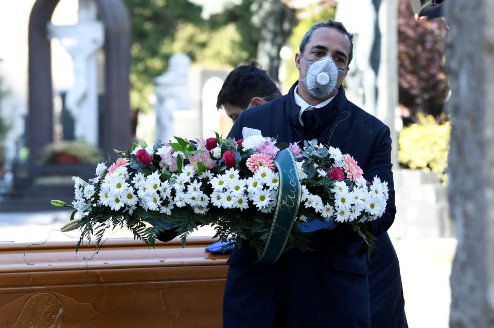  Cemetery workers and funeral agency workers in protective masks transport a coffin in Bergamo