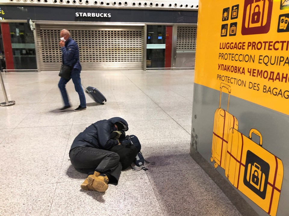  A traveller rests on his bag on the floor at the airport in Malaga, Spain