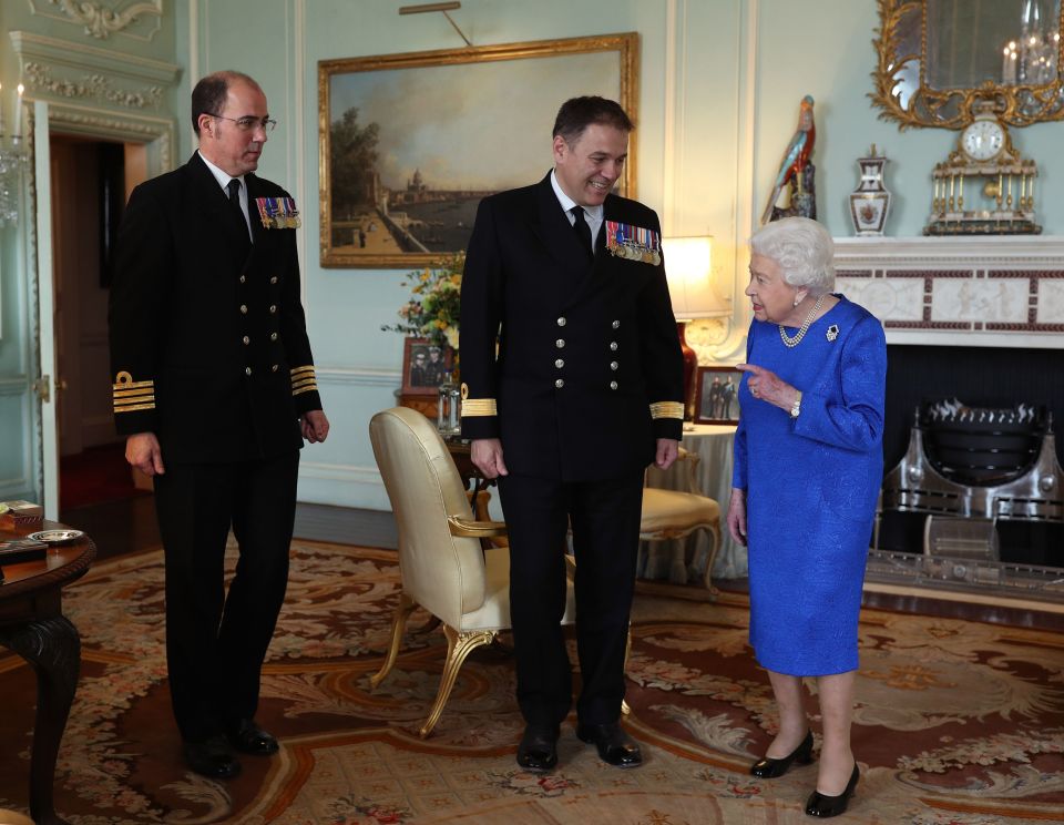 Harry has urged his grandmother to take 'extra precautions' and she avoided her usual handshake when meeting Commodore Steven Moorhouse (centre, outgoing Commanding Officer, HMS Queen Elizabeth) and Captain Angus Essenhigh (incoming Commanding Officer) at Buckingham Palace today