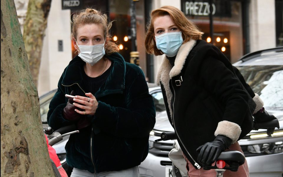  Two women wear face masks as emergency measures are announced