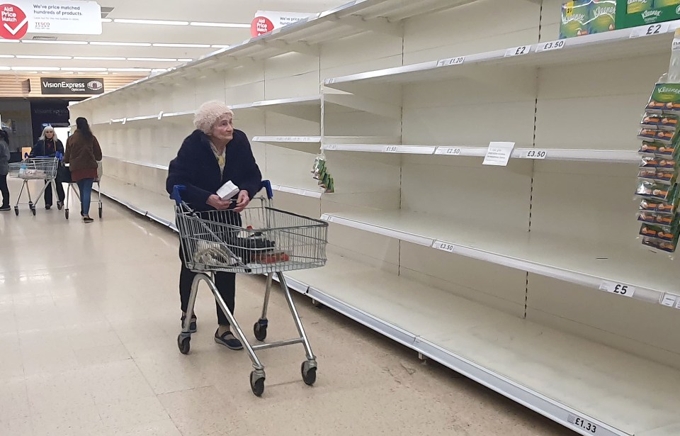  An elderly woman walks between the empty shelves in Kent