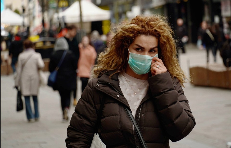 A woman walks through the street in a face mask