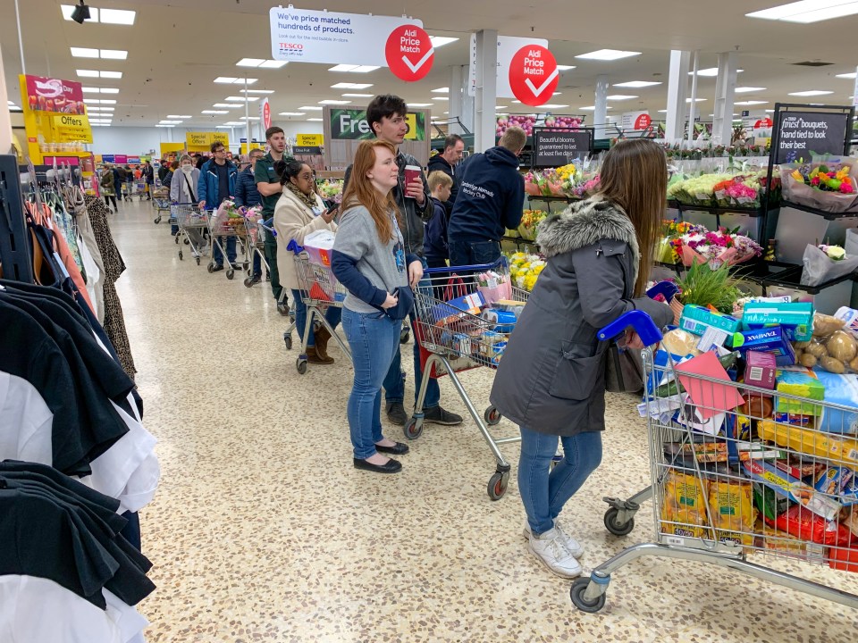  Shoppers with packed trolleys queue up to pay