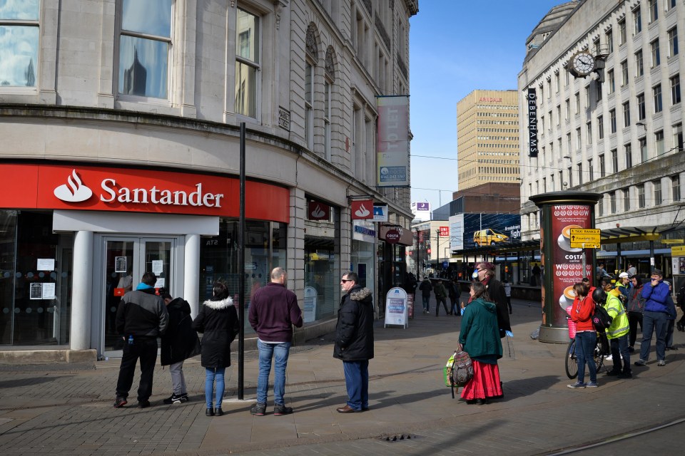  Customers stand apart outside a branch of Santander in Manchester