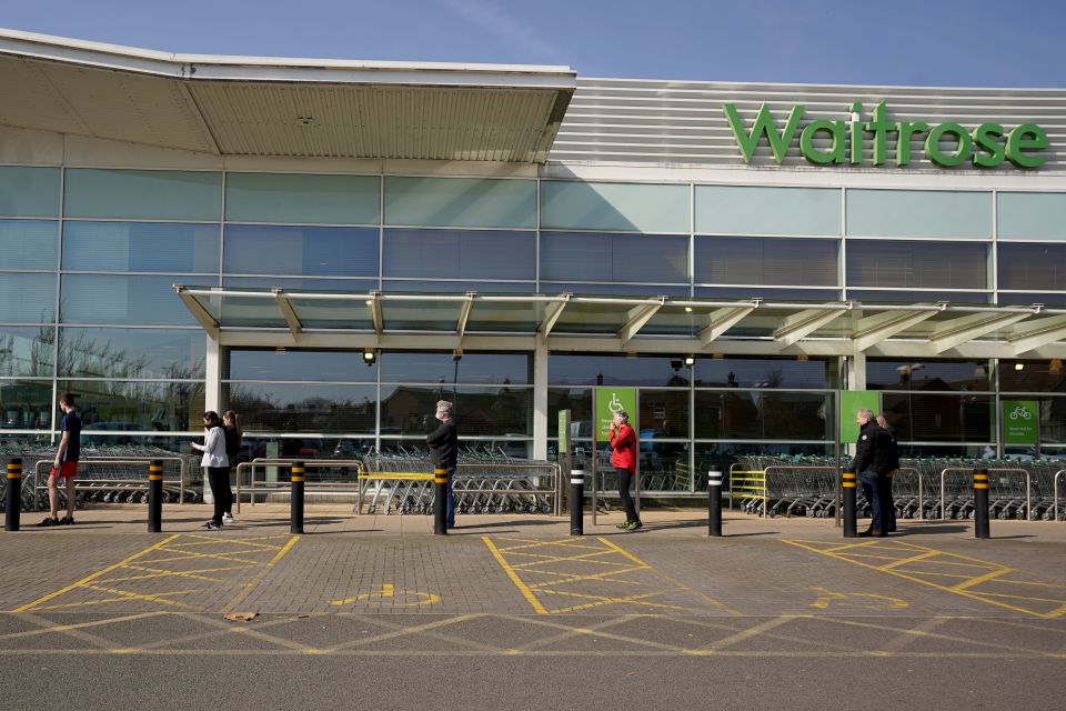  People observe social distancing while queuing at a Waitrose supermarket in Lichfield,