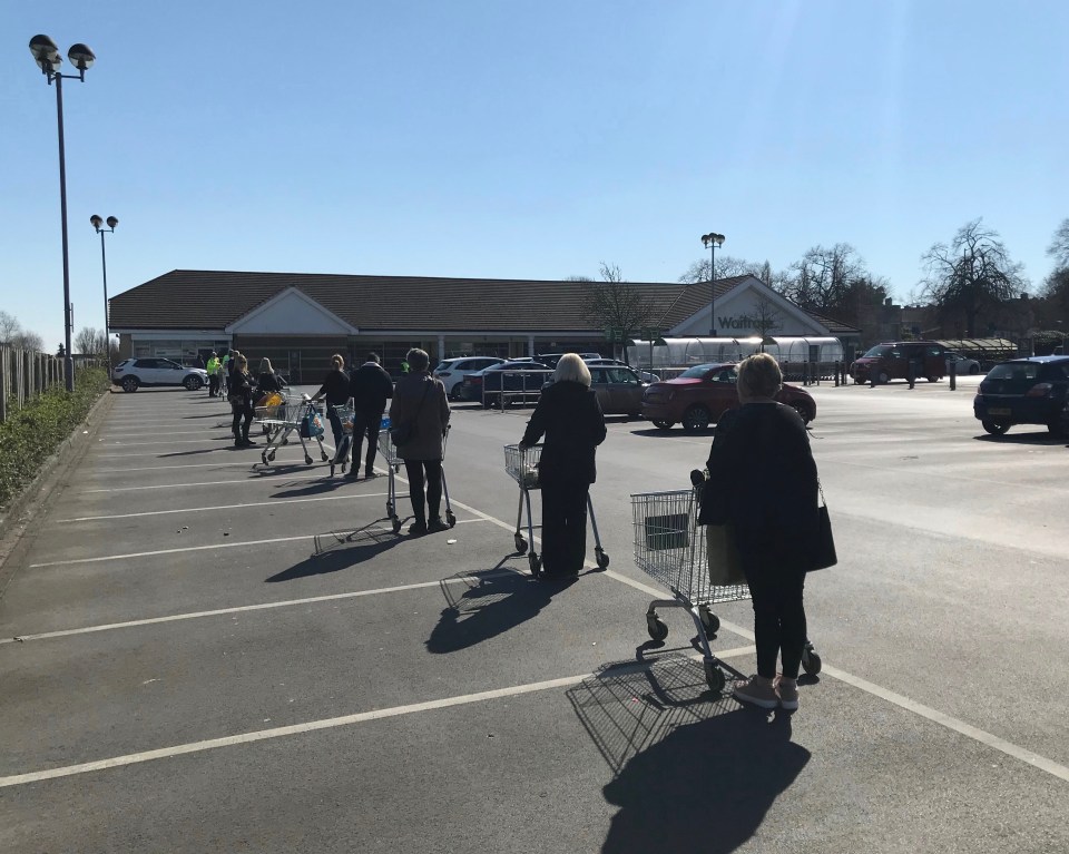 Shoppers observe social distancing rules as they queue along the car park outside Waitrose in Reading.