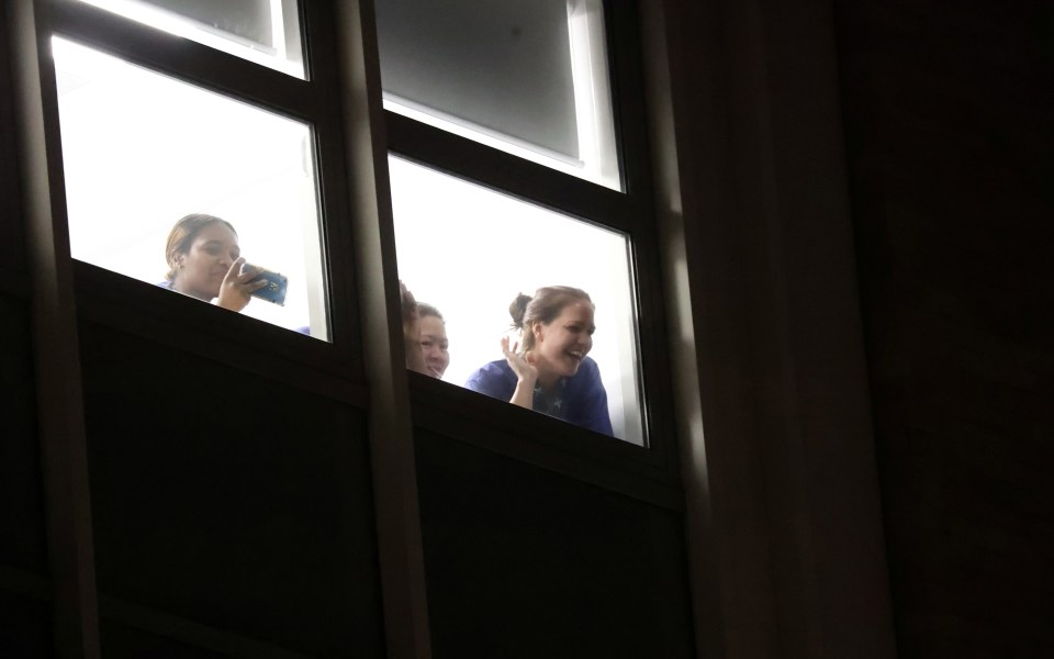 Staff from Chelsea and Westminster Hospital glance out a window at those supporting them