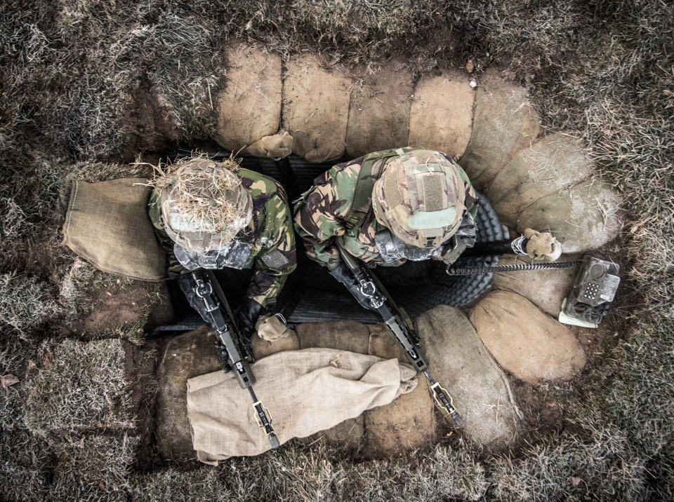  Two British Army soldiers huddle in a sandbagged trench