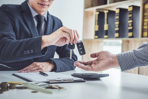 Salesperson handing car keys to customer.