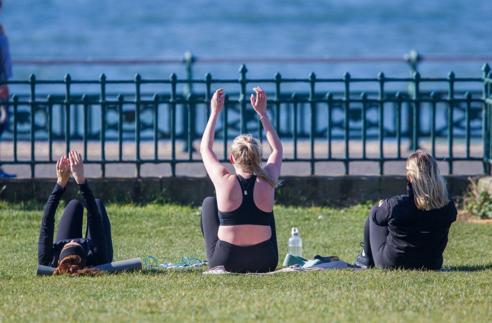  Three women in Brighton stretch closely together as it's been warned that there could be a total ban on exercising outdoors