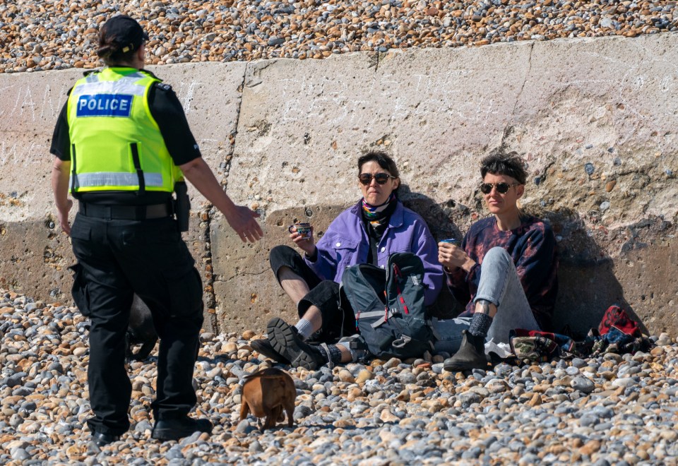  Police speak to two people sat on Brighton beach enjoying a coffee