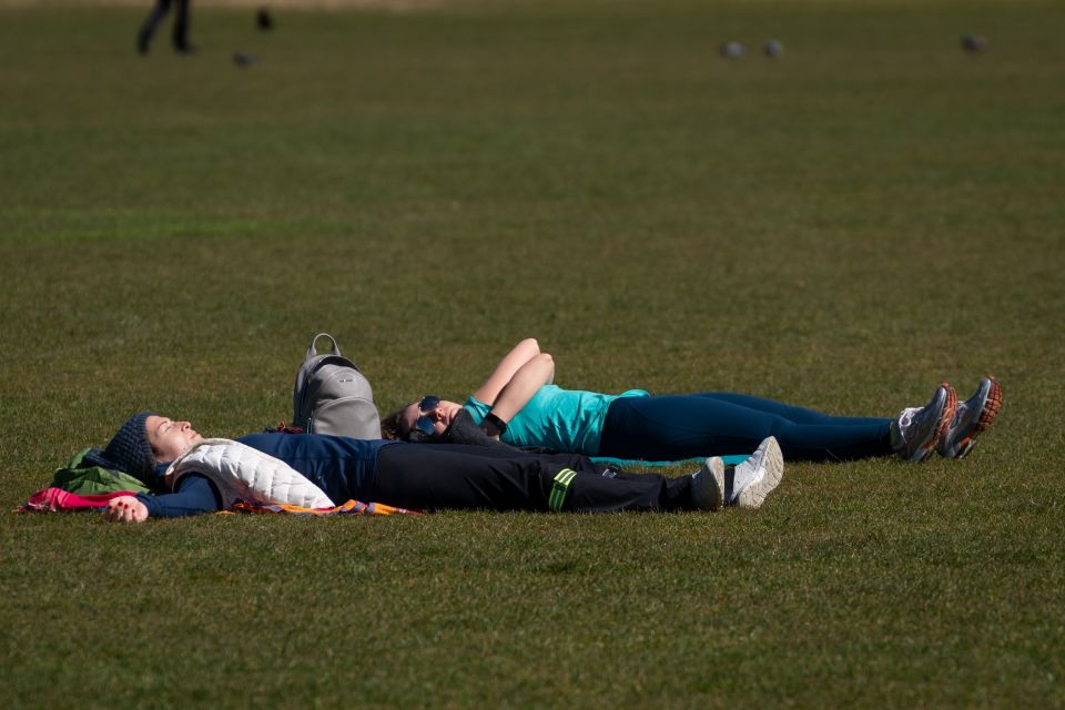  Two people sun bathe in Regent's Park during the hottest day of the year so far