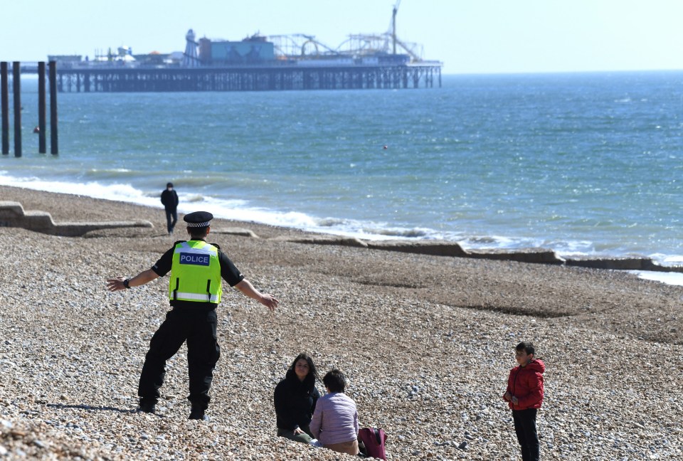 A police officer asks people to leave the beach in Brighton on a sunny Sunday during the Covid-19 outbreak