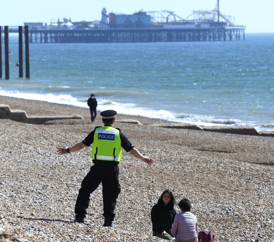  A police officer asks people to leave the beach in Brighton on a sunny day during the Covid-19 outbreak