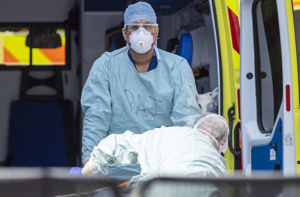  NHS workers in PPE take a patient from an ambulance at St Thomas' Hospital