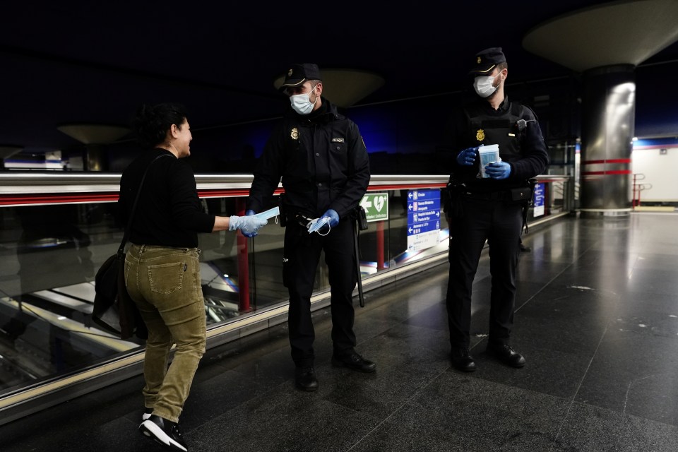  Police officers giving out free protective face masks at a Madrid metro station