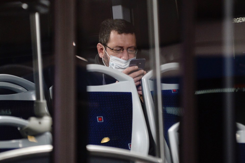  A worker, with a protective mask, looks at his mobile phone on bus to going to work in Valladolid