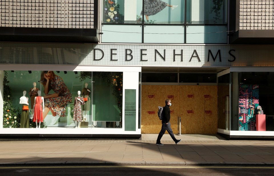  Shoppers walk past boarded up stores as the UK lockdown continues