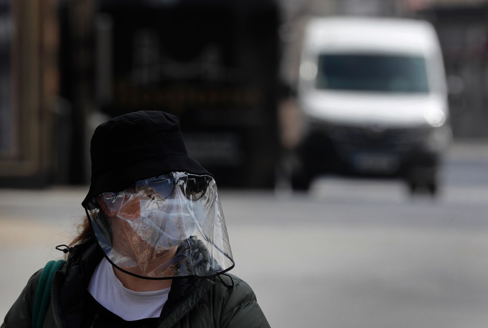  A woman in a mask walks through London today