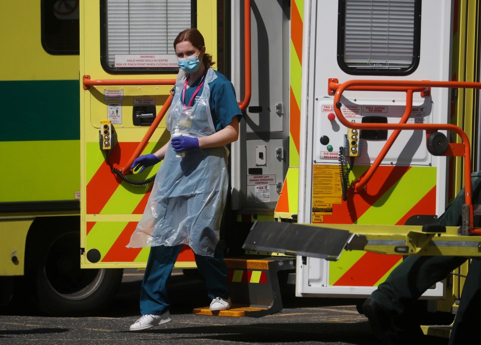  A medical worker wearing personal protective equipment (PPE) at the back of an ambulance outside Lewisham hospital in London