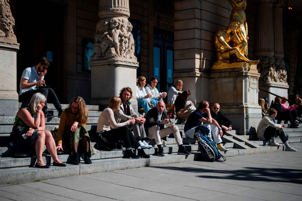  People sit and enjoy the spring weather outside the Royal Dramatic Theatre in Stockholm amid coronavirus death toll rise