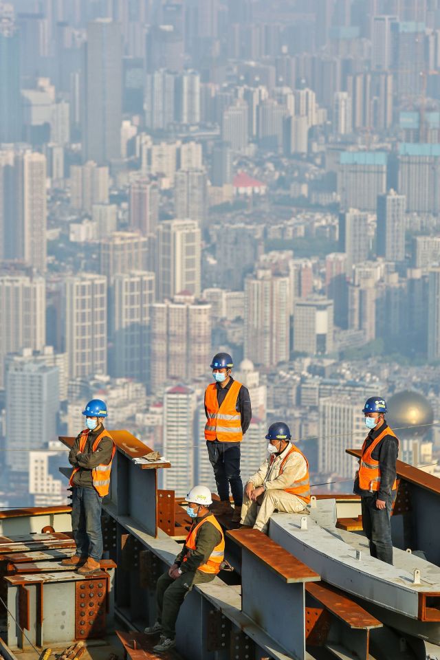  Employees wear face masks as they work at the construction site of the Wuhan Greenland Centre